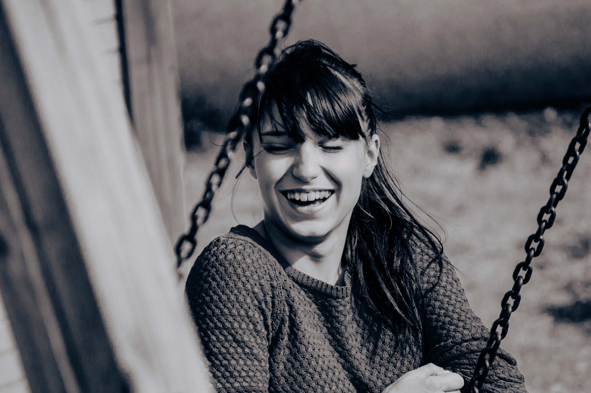 Photographie de portrait, femme sur balançoire, rit aux éclats, photographie en noir et blanc